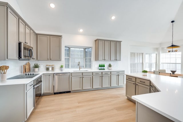 kitchen featuring tasteful backsplash, gray cabinetry, stainless steel appliances, sink, and a chandelier