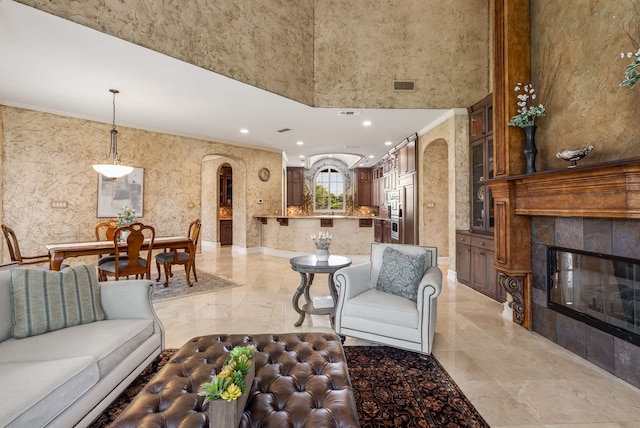 living room with crown molding, a towering ceiling, and a fireplace