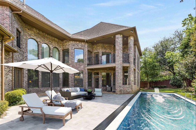 back of house with a fenced in pool, a patio area, an outdoor living space, and a balcony