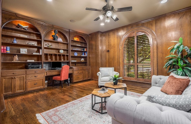 office space featuring built in desk, dark hardwood / wood-style flooring, ceiling fan, and wooden walls