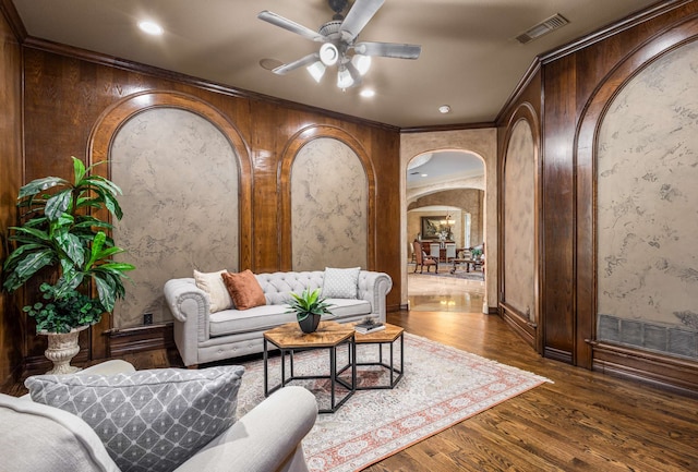 living room featuring dark hardwood / wood-style flooring, ceiling fan, and ornamental molding