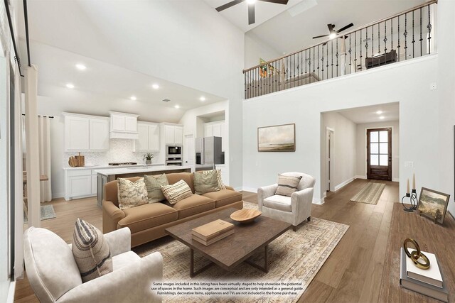 living room with light wood-type flooring, high vaulted ceiling, and ceiling fan