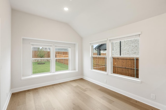 spare room with light hardwood / wood-style floors and lofted ceiling