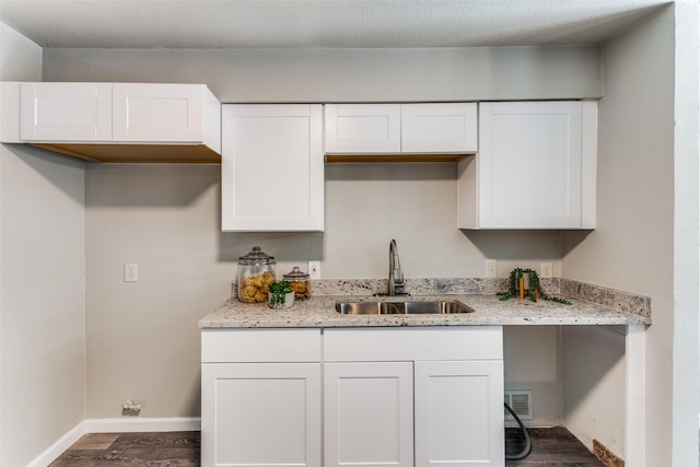 kitchen featuring dark wood-type flooring, a sink, white cabinetry, and visible vents