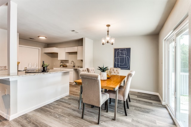 dining room featuring an inviting chandelier, light wood-type flooring, and sink