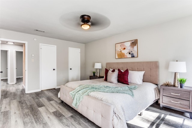 bedroom with visible vents, a ceiling fan, baseboards, and wood finished floors