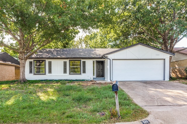 ranch-style house featuring an attached garage, a shingled roof, a front yard, and concrete driveway
