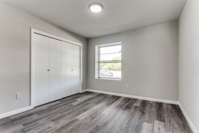 unfurnished bedroom featuring a closet, baseboards, and wood finished floors