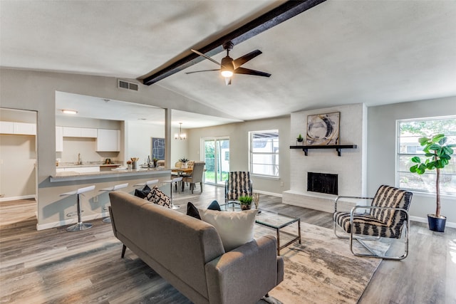 living room with vaulted ceiling with beams, a fireplace, light hardwood / wood-style floors, and a healthy amount of sunlight