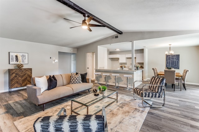 living room with ceiling fan with notable chandelier, lofted ceiling with beams, and hardwood / wood-style floors