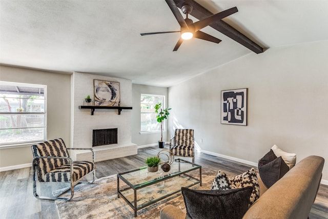 living area with baseboards, a ceiling fan, wood finished floors, and a fireplace