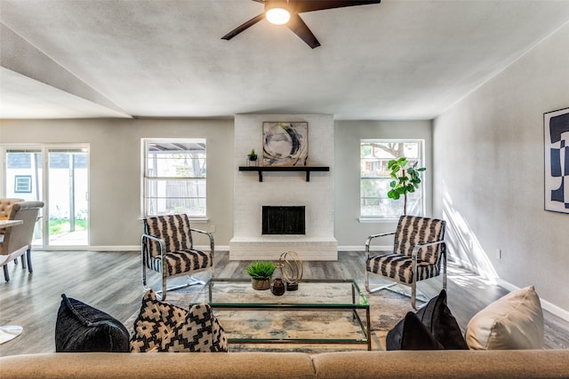 living room with ceiling fan, a fireplace, and light hardwood / wood-style floors