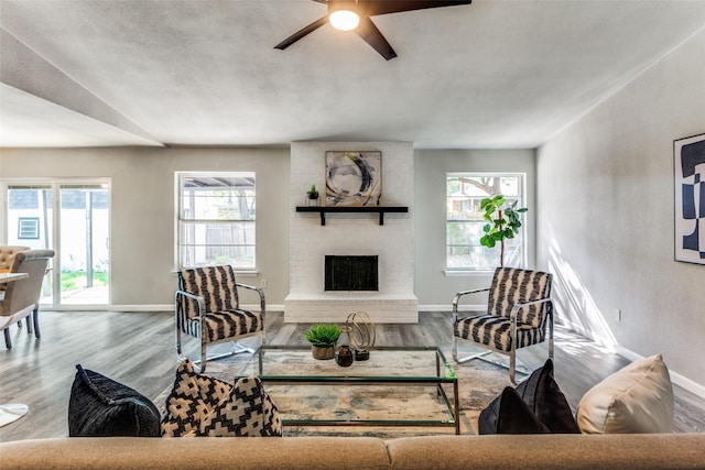 living area with baseboards, ceiling fan, wood finished floors, and a fireplace
