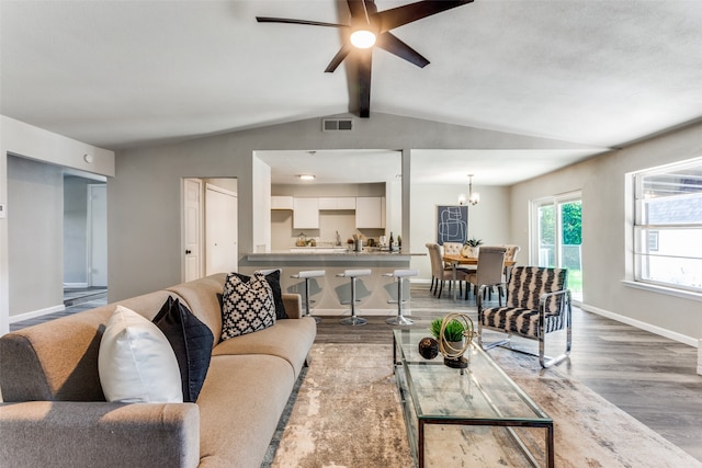 living room featuring hardwood / wood-style flooring, ceiling fan with notable chandelier, and lofted ceiling with beams