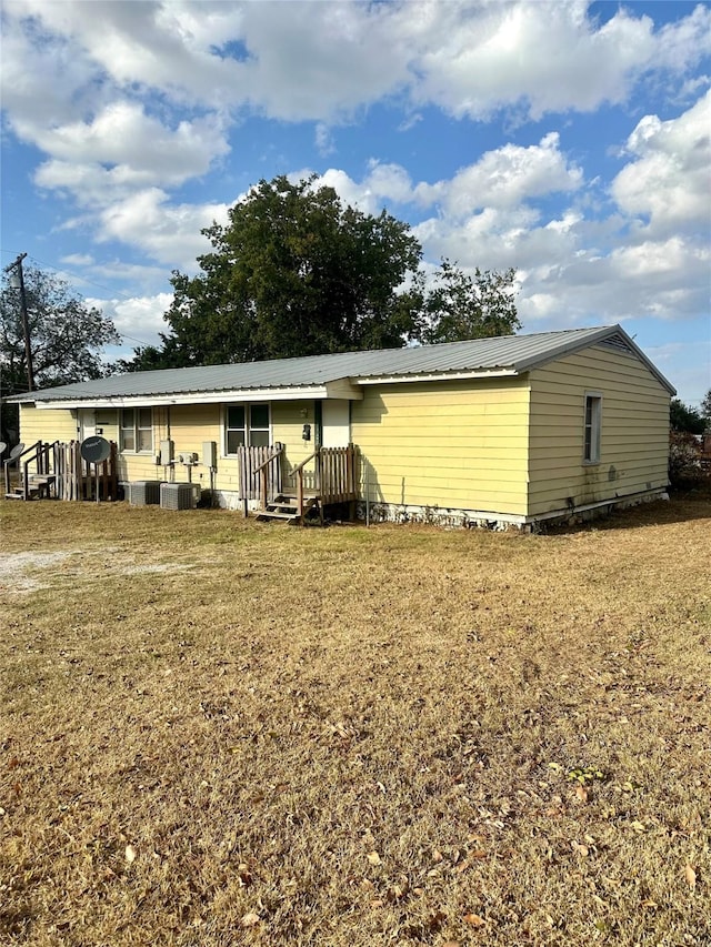 rear view of house featuring a lawn and central AC