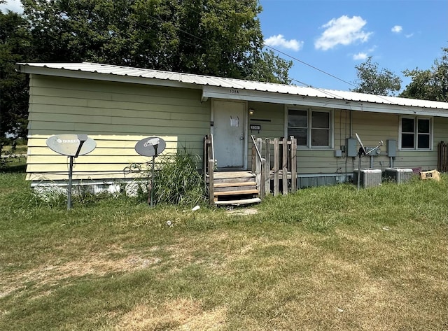 view of front facade with cooling unit and a front lawn