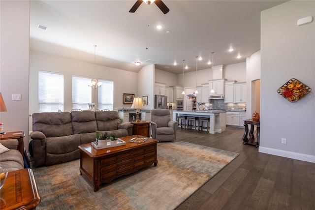 living room featuring ceiling fan with notable chandelier, sink, and dark hardwood / wood-style flooring