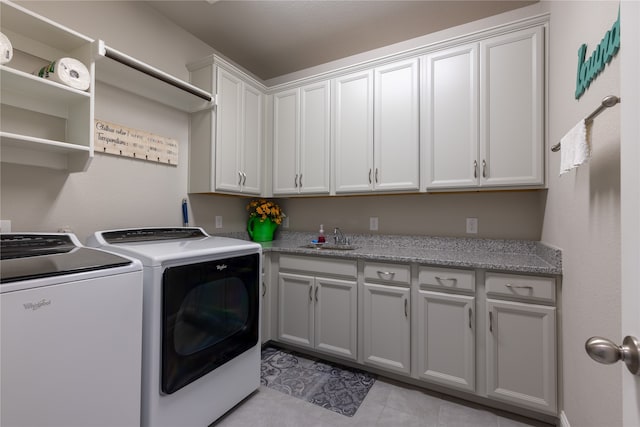 washroom with light tile patterned floors, sink, washer and dryer, and cabinets