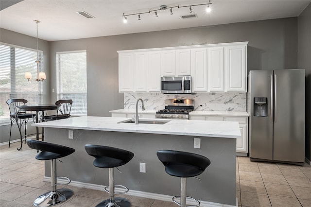 kitchen with sink, a kitchen island with sink, backsplash, white cabinetry, and appliances with stainless steel finishes