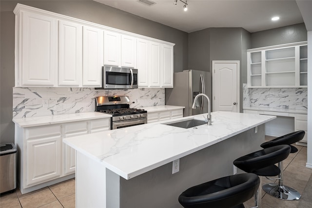 kitchen with a center island with sink, stainless steel appliances, sink, and white cabinetry