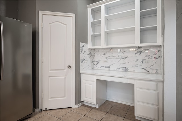 kitchen with decorative backsplash, white cabinets, light tile patterned floors, and stainless steel fridge