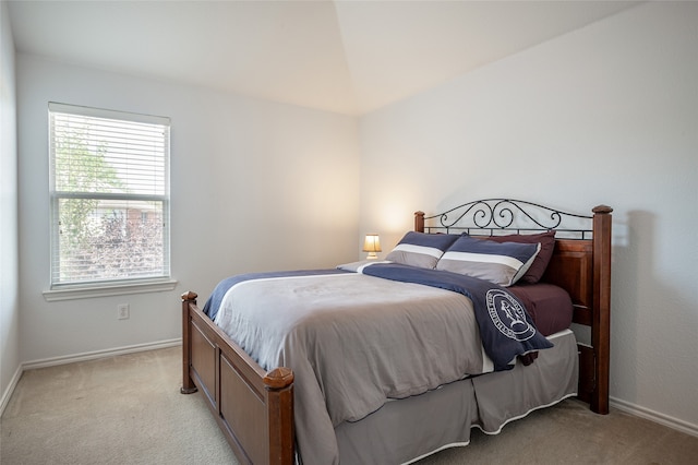 bedroom with lofted ceiling, multiple windows, and light colored carpet