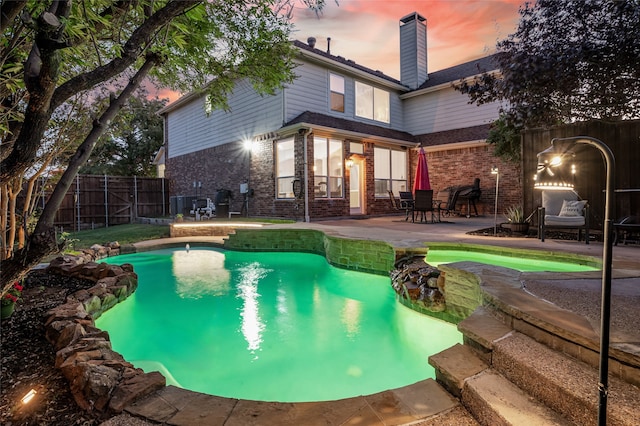 pool at dusk with a patio area