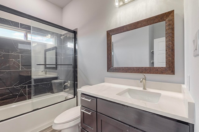 full bathroom featuring combined bath / shower with glass door, vanity, and toilet