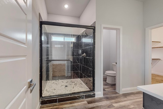 bathroom featuring vanity, hardwood / wood-style flooring, a shower with shower door, and toilet