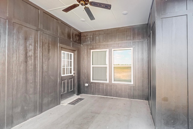 unfurnished room with ceiling fan and wood walls