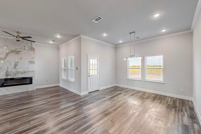 unfurnished living room featuring a high end fireplace, ceiling fan, a healthy amount of sunlight, and dark hardwood / wood-style flooring