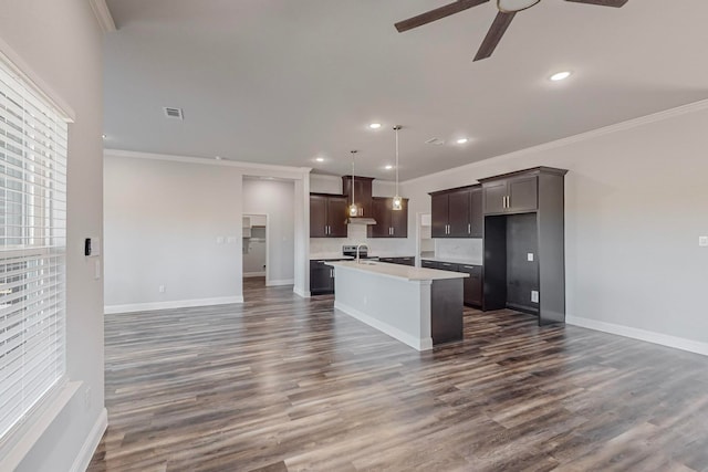 kitchen with ceiling fan, a center island with sink, and ornamental molding