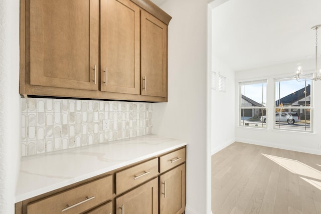 kitchen featuring light stone countertops, light hardwood / wood-style flooring, decorative light fixtures, and an inviting chandelier