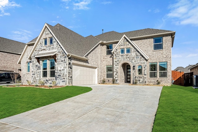 tudor home with cooling unit, a front yard, and a garage