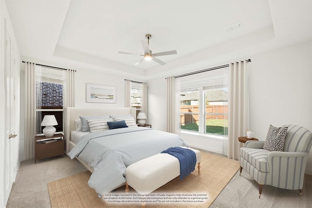 carpeted bedroom with a raised ceiling and ceiling fan