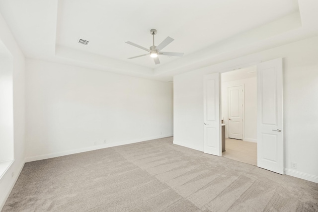 carpeted spare room featuring ceiling fan and a raised ceiling