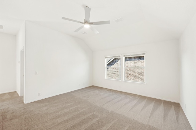 spare room with ceiling fan, light colored carpet, and vaulted ceiling