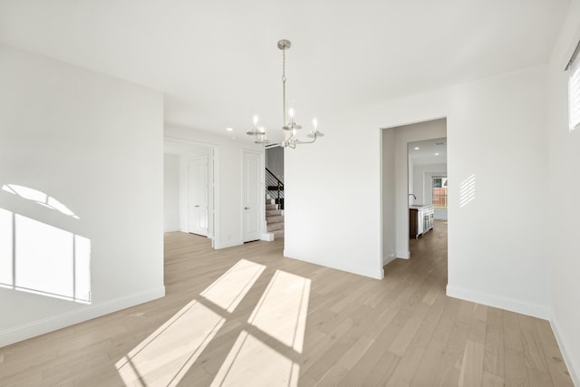 unfurnished dining area with an inviting chandelier and light hardwood / wood-style flooring