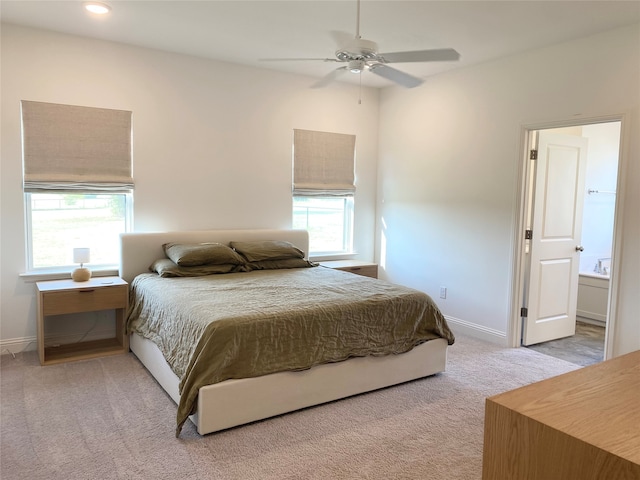 carpeted bedroom featuring ensuite bath, multiple windows, and ceiling fan