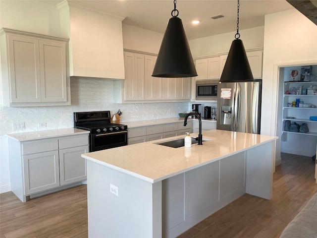 kitchen with hanging light fixtures, appliances with stainless steel finishes, light wood-type flooring, and sink