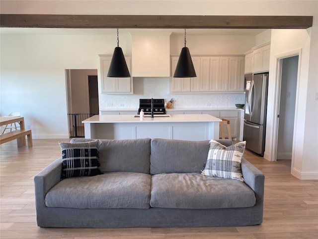 living room featuring sink, light hardwood / wood-style flooring, and beam ceiling