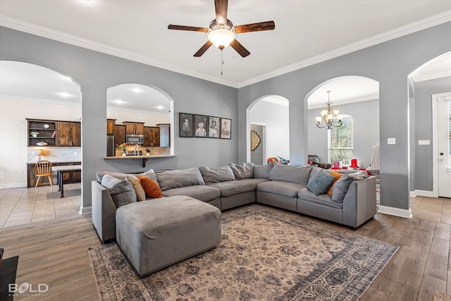 living room featuring ceiling fan with notable chandelier, ornamental molding, and hardwood / wood-style floors