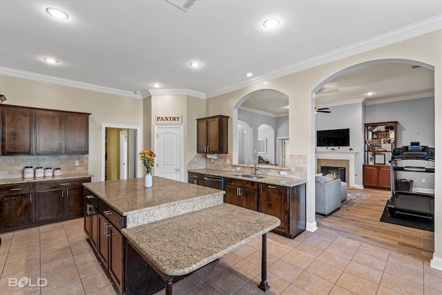 kitchen featuring tasteful backsplash, sink, a kitchen island, ornamental molding, and ceiling fan