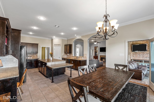 tiled dining space with ceiling fan with notable chandelier, ornamental molding, and sink