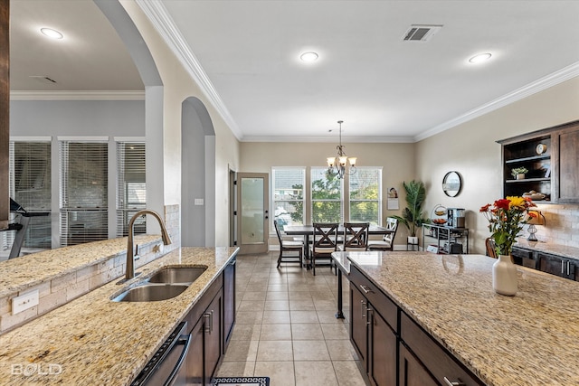 kitchen with light stone countertops, a chandelier, sink, and crown molding