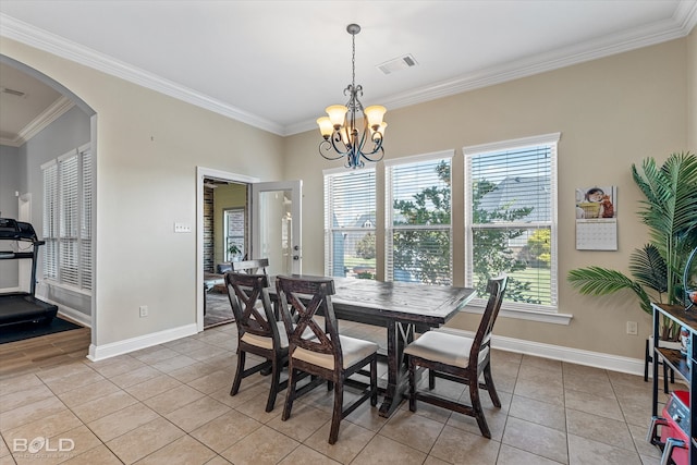 tiled dining area with ornamental molding, an inviting chandelier, and a healthy amount of sunlight