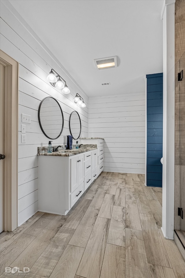 bathroom with wood walls, hardwood / wood-style flooring, and vanity