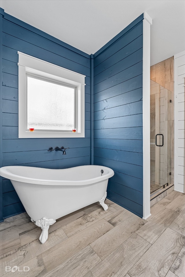 bathroom with wood walls, independent shower and bath, and hardwood / wood-style floors