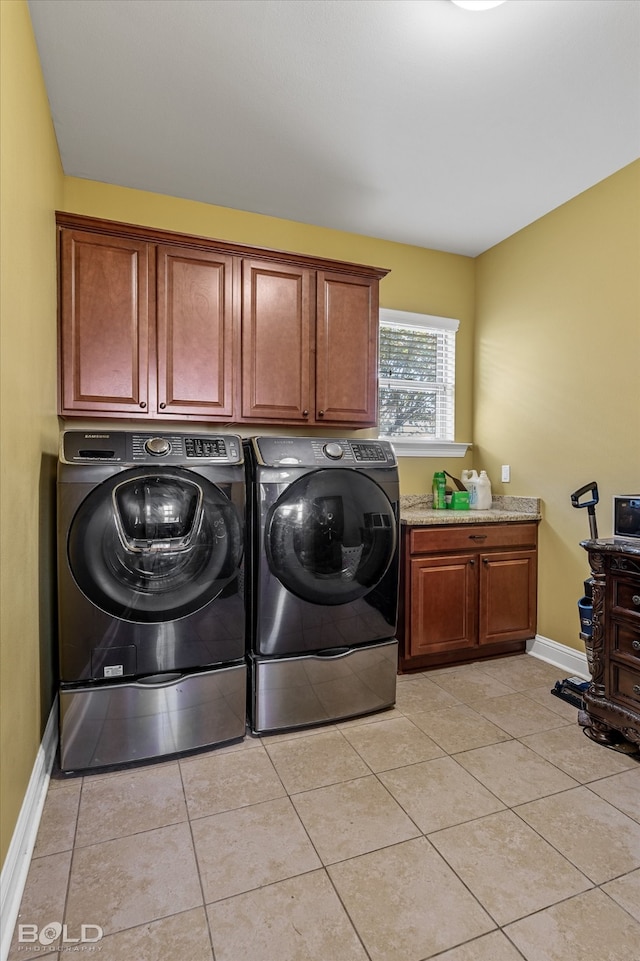 washroom featuring light tile patterned floors, washing machine and clothes dryer, and cabinets