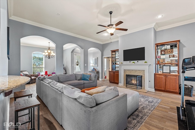 living room featuring light hardwood / wood-style flooring, ceiling fan with notable chandelier, and ornamental molding